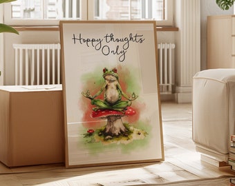 Könnte beinhalten: Ein gerahmtes Aquarellbild eines grünen Frosches, der auf einem roten Pilz meditiert. Der Text "Hoppy Thoughts Only" ist in schwarzer Kursivschrift über dem Frosch geschrieben.