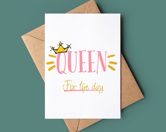 Könnte beinhalten: Eine weiße Karte mit dem Text "QUEEN" in Rosa und einer gelben Kronengrafik. Der Text "For the day" ist in Kursivschrift unter dem Wort "QUEEN" geschrieben.