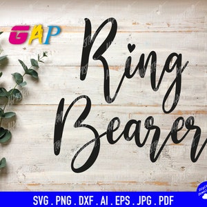 Op de afbeelding: Een digitaal grafisch ontwerp met de zwarte tekst Ring Bearer in een cursief lettertype met een klein hartje boven de letter i. Links staat een groene eucalyptusstengel. De achtergrond is een witte textuur van houten planken.