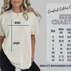 Puede incluir: Una camiseta color crema con una tabla de tallas. La tabla enumera las tallas S a 4XL, con medidas de ancho y largo en pulgadas. El texto "Comfort Colors C1717" est&aacute; en la parte superior. La modelo usa una talla mediana.
