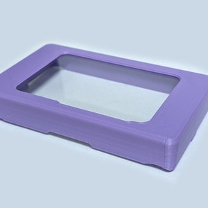 以下が含まれることがあります： 透明な窓が付いたラベンダー色のプラスチックケース。ケースは小型の電子機器を入れるように設計されています。
