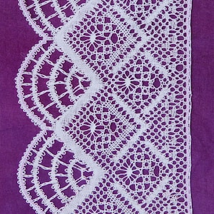 May include: White lace trim with a scalloped edge against a purple background. The lace has a delicate floral pattern.