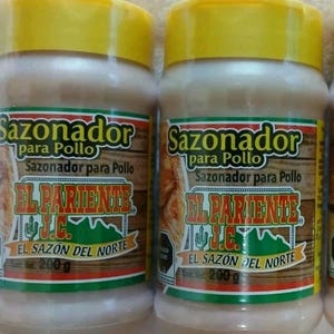 May include: Two plastic spice containers with yellow lids. The labels read "Sazonador para Pollo" and "El Pariente J.C. El Sazón Del Norte". Each container holds 200g of seasoning. The labels feature a wood-grain design with a green and red border.