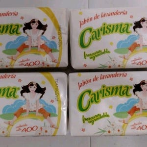 May include: Four rectangular bars of Carisma laundry soap in white plastic packaging. Each label features a cartoon illustration of a person with dark hair, the text Jabón de lavandería Carisma, and the weight clearly printed as 400 g.