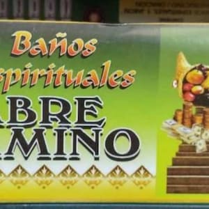 May include: Box with the text "7 Baños Espirituales ABRE CAMINO" in white and orange letters on a green background. The box features a cornucopia, coins, money, a cross, and a heart.
