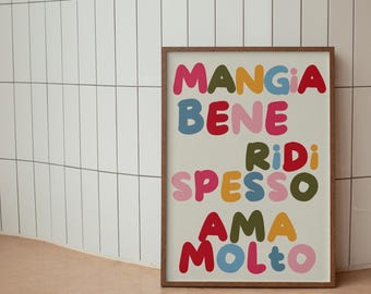 May include: A framed print with the text "Mangia Bene, Ridi Spesso, Ama Molto" in colorful, bubble-like letters on a cream background. The frame is brown wood.