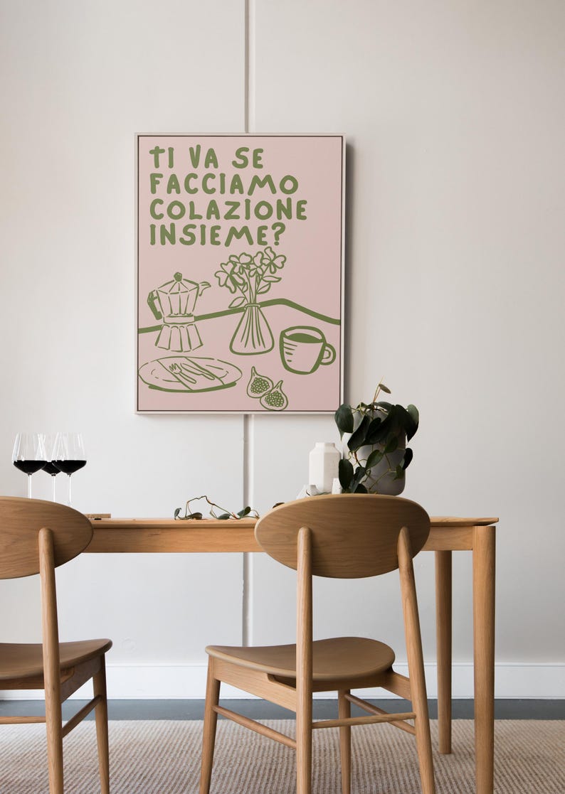 May include: A pink and green illustration of a breakfast scene with a coffee pot, a cup of coffee, a plate with cutlery, a vase of flowers, and figs. The text reads "Ti va se facciamo colazione insieme?"