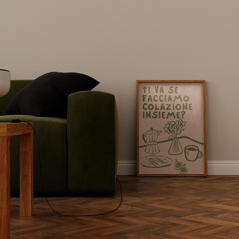 May include: A framed print with a pink background and green text that reads "Ti va se facciamo colazione insieme?"  The print features a green illustration of a coffee pot, a vase of flowers, a plate with a fork and knife, and a cup of coffee.