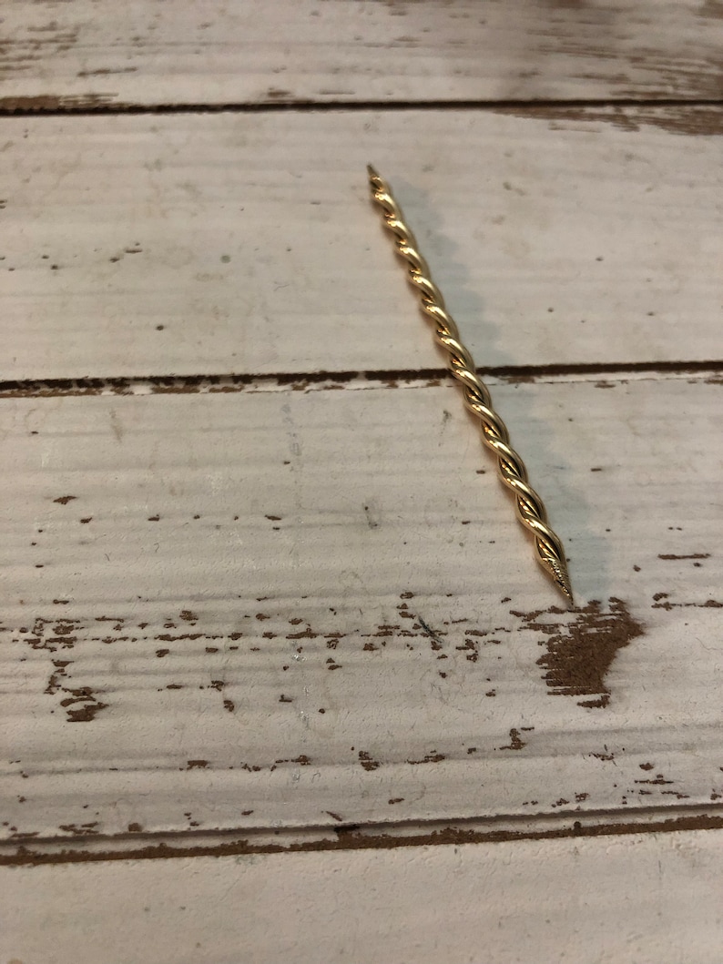Peut inclure: Une tige en m&eacute;tal torsad&eacute;e de couleur dor&eacute;e avec une pointe.