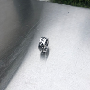 Puede incluir: Un anillo de plata con un diseño trenzado.