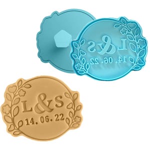 May include: Two cookie cutters, one blue and one brown, with a floral design and the text "L&S 14.06.22" and "L&S 14.06.22".