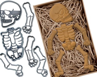 May include: A set of cookie cutters in the shape of a skeleton. The cutters are made of metal and are silver in colour. The set includes a skull, rib cage, and two sets of arms and legs.