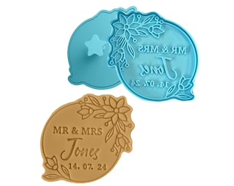 Pode incluir: Dois cortadores de biscoitos, um azul e outro marrom, com um design floral e o texto "MR & MRS Jones 14. 07. 24".