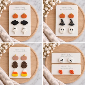 May include: Four sets of stud earrings on white display cards labelled emmi clay handcrafted jewellery. Designs include orange pumpkins, black bats, white ghosts, black witch hats, white mummies, brown pinecones, candy corn, skulls, and orange leaves.