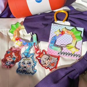Puede incluir: Una botella de agua naranja y blanca con las letras "TP" y una tapa verde. Tambi&eacute;n varios llaveros de personajes de estilo anime con marcos coloridos en forma de estrella y una etiqueta con el texto "x99999999".