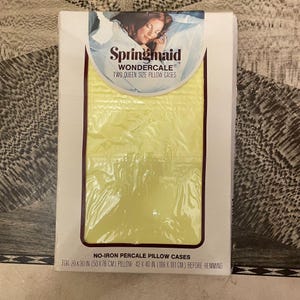 May include: A package of Springmaid Wondercale two queen size pillow cases. The pillowcases are a pale yellow color and are made of no-iron percale. The package dimensions are 20 x 30 inches (50 x 76 cm) for the pillow and 42 x 40 inches (106 x 101 cm) before hemming.