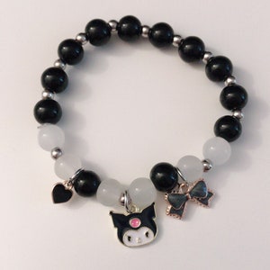 Op de afbeelding: Zwart-witte kralen armband met een zwart hart, een zwart-witte strik en een zwart-witte figuur bedel.