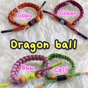 May include: Four colorful woven bracelets with different characters from the Dragon Ball anime series. The bracelets are orange, purple, pink, and green with yellow beads and black accents. The characters are Goku, Gohan, Buu, and Cell.
