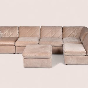 May include: A modular sectional sofa in a light beige velvet fabric featuring a diagonal quilted pattern across the backrests and seat cushions. The set includes multiple connected seating units arranged in an L-shape with a matching square ottoman.