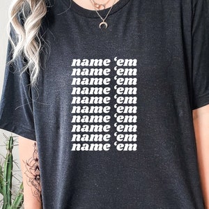 Puede incluir: Camiseta negra con la frase "name 'em" repetida varias veces en texto blanco.