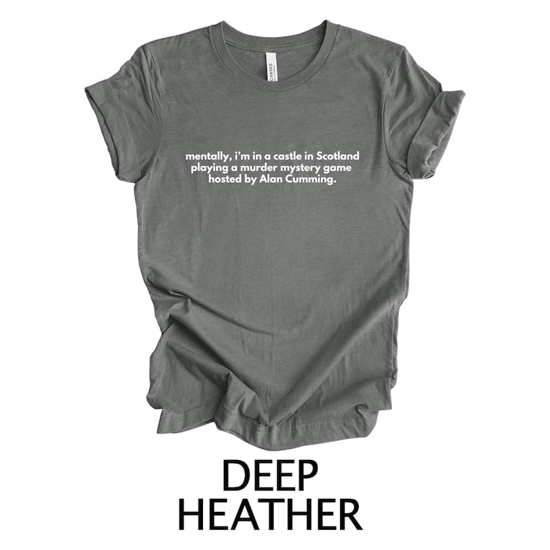 May include: A dark heather grey t-shirt with the text "mentally, I'm in a castle in Scotland playing a murder mystery game hosted by Alan Cumming."