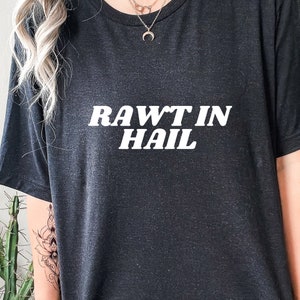 Könnte beinhalten: Schwarzes T-Shirt mit weißem Text, der "RAW'T IN HAIL" lautet.