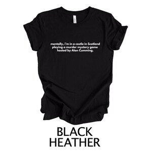 May include: Black heather t-shirt with white text that reads "mentally, I'm in a castle in Scotland playing a murder mystery game hosted by Alan Cumming."