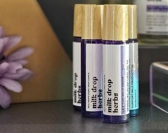 May include: Four small glass bottles with wooden caps and purple liquid. The bottles are labeled "milk drop herbs" and have a blue and purple glitter effect.