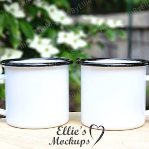 May include: Two white enamel mugs with black rims, sitting on a wooden surface. The mugs are blank and ready for customization.