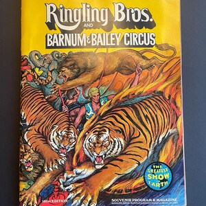 May include: A vintage program for the Ringling Bros. and Barnum & Bailey Circus. The cover features a colorful illustration of tigers and a lion, with the text "The Greatest Show on Earth" in a circle.