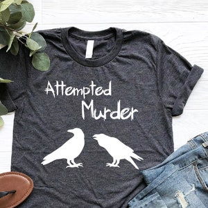 a t - shirt that says attempted murder with two crows on it