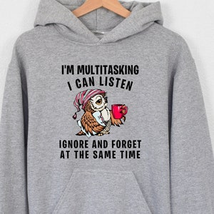 May include: Gray hooded sweatshirt with a graphic of an owl holding a red mug. The text on the sweatshirt reads "I'm multitasking I can listen ignore and forget at the same time."