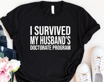 I Survived My Husband’s Doktorate Program Shirt, Husband Phd Graduation Shirt, Doctorate Degree Shirt, Gift For Academician’s Wife, Wife Tee