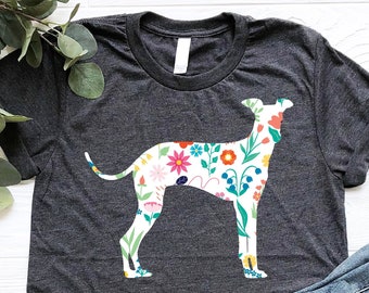May include: A dark gray t-shirt with a floral patterned silhouette of a dog. The shirt is paired with blue jeans and brown sandals.