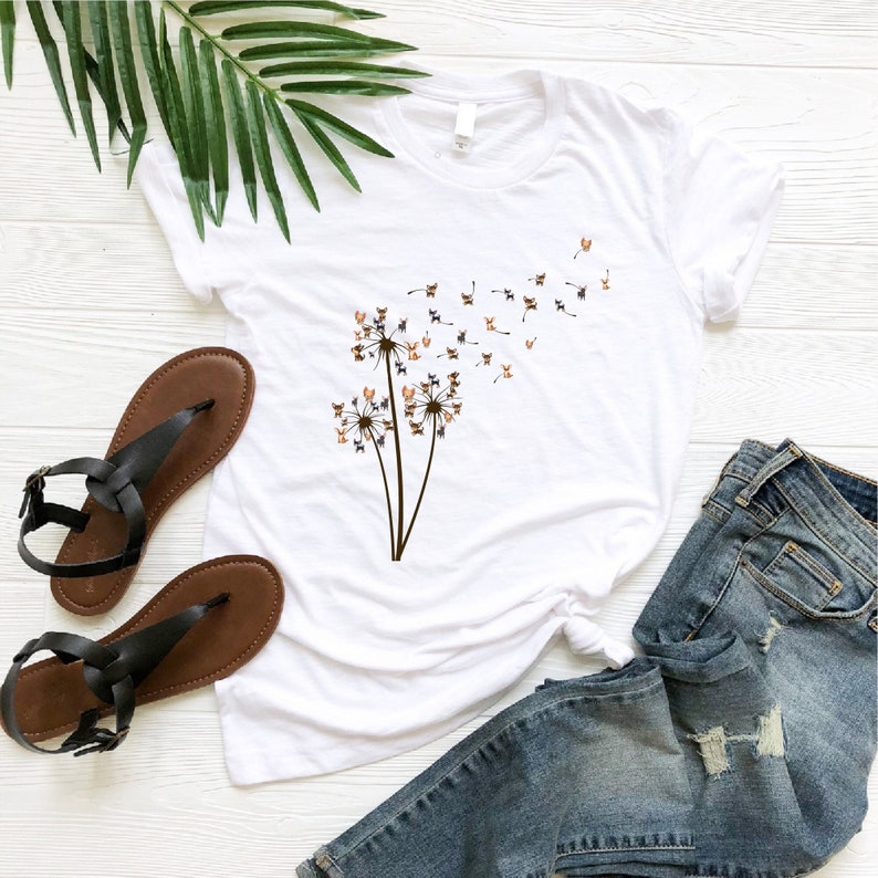 a t - shirt with a dandelion on it next to a pair of