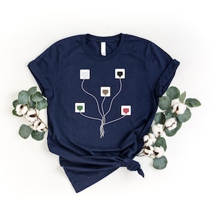 May include: A navy blue t-shirt with a graphic of a tree with five different colored electrical outlets connected to the roots. The outlets are white, brown, green, red, and black.