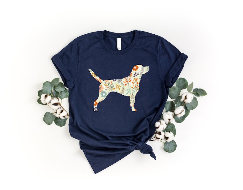 Pode incluir: Uma camiseta azul marinho com uma silhueta de c&atilde;o com padr&atilde;o floral na frente.