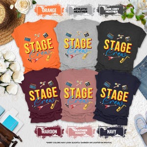 May include: Six short-sleeved t-shirts in orange, athletic heather, dark grey heather, maroon, heather mauve, and navy. Each shirt features the text STAGE Crew in yellow and blue, surrounded by musical instrument icons like drums and saxophones.
