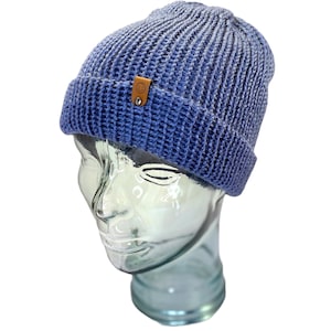 May include: A blue knitted beanie with a brown leather patch featuring a smiley face.