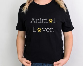 Op de afbeelding: Zwart T-shirt met witte tekst die "Animal Lover" zegt. De tekst is versierd met gele poot afdrukken.