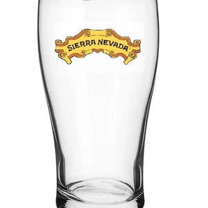 May include: A clear glass pint glass with a yellow and orange logo that reads "Sierra Nevada".
