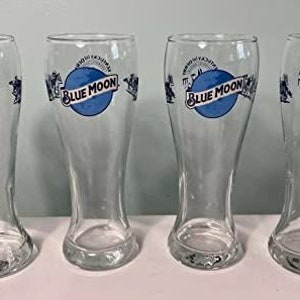 May include: Four clear glass beer mugs with a blue moon logo and the words "Blue Moon" printed on the front.