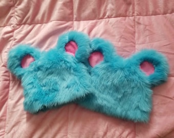 May include: Two blue fuzzy earmuffs with pink ears. The earmuffs are made of soft, fluffy material and are perfect for keeping your ears warm in the winter.