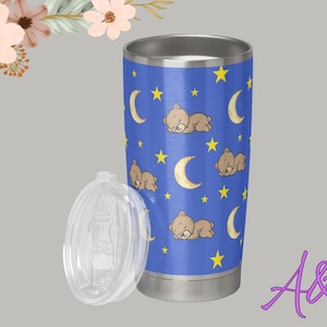 May include: A blue stainless steel tumbler with a clear lid. The tumbler features a pattern of sleeping teddy bears, yellow crescent moons, and stars. The tumbler is approximately 7 inches tall.