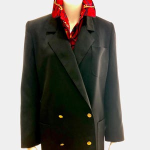May include: A black double-breasted blazer with gold buttons and a patch pocket. The blazer is worn over a red and gold patterned shirt.
