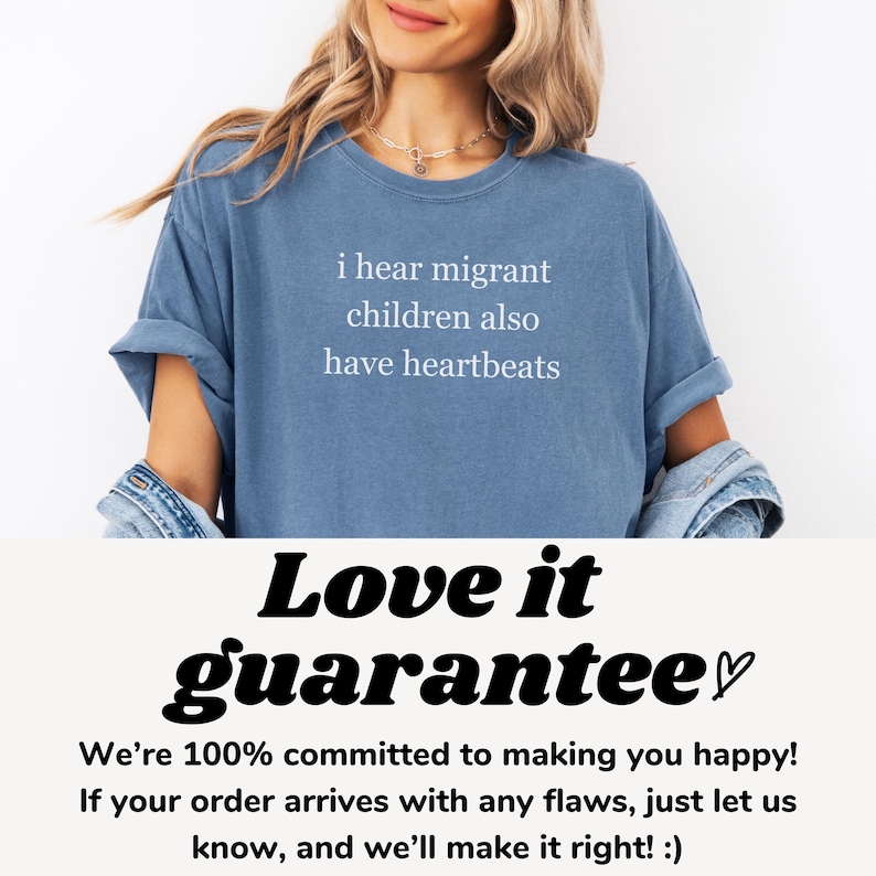 Pu&ograve; includere: Una maglietta blu con la scritta bianca "i hear migrant children also have heartbeats". La maglietta &egrave; indossata da una persona. La parte inferiore dell'immagine presenta le parole "Love it guarantee" in grassetto e corsivo.