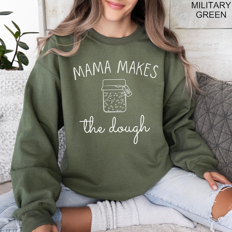 May include: A green sweatshirt with the text "Mama Makes the Dough" and a drawing of a jar with a label that says "Dough".