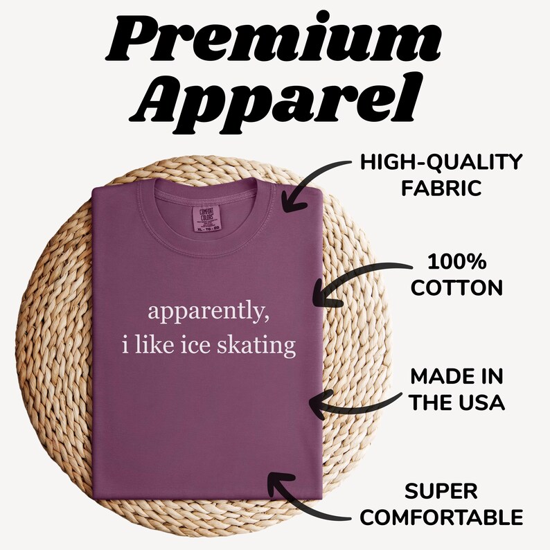 May include: A folded, mauve-colored t-shirt with the text "apparently, i like ice skating" in white. The shirt is displayed on a woven, circular surface. Text in the image indicates it is made of high-quality fabric, 100% cotton, and made in the USA.