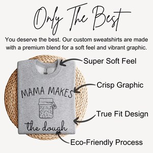 May include: Gray sweatshirt with a graphic of a jar that says "Mama Makes the Dough". The sweatshirt is on a woven mat with text highlighting the features of the sweatshirt: "Super Soft Feel", "Crisp Graphic", "True Fit Design", and "Eco-Friendly Process".