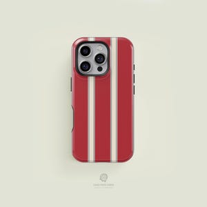 May include: A red and cream striped phone case. The case has a vertical stripe pattern with a red background and cream-colored stripes. The phone case has a camera cutout and the words "CASE FACE CASES" are printed at the bottom.